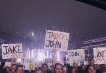 Taylor Swift’s Complete Relationship Timeline: Every Man, Every Era Rain-streaked window view of a concert crowd holding up signs with ex-boyfriend names (like John, Jake, Joe, Harry) crossed out.