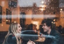 Sabrina Carpenter x Joshua Bassett: Back Together or Just PR? "Rainy window view of a couple holding hands in a cafe, smiling at each other."